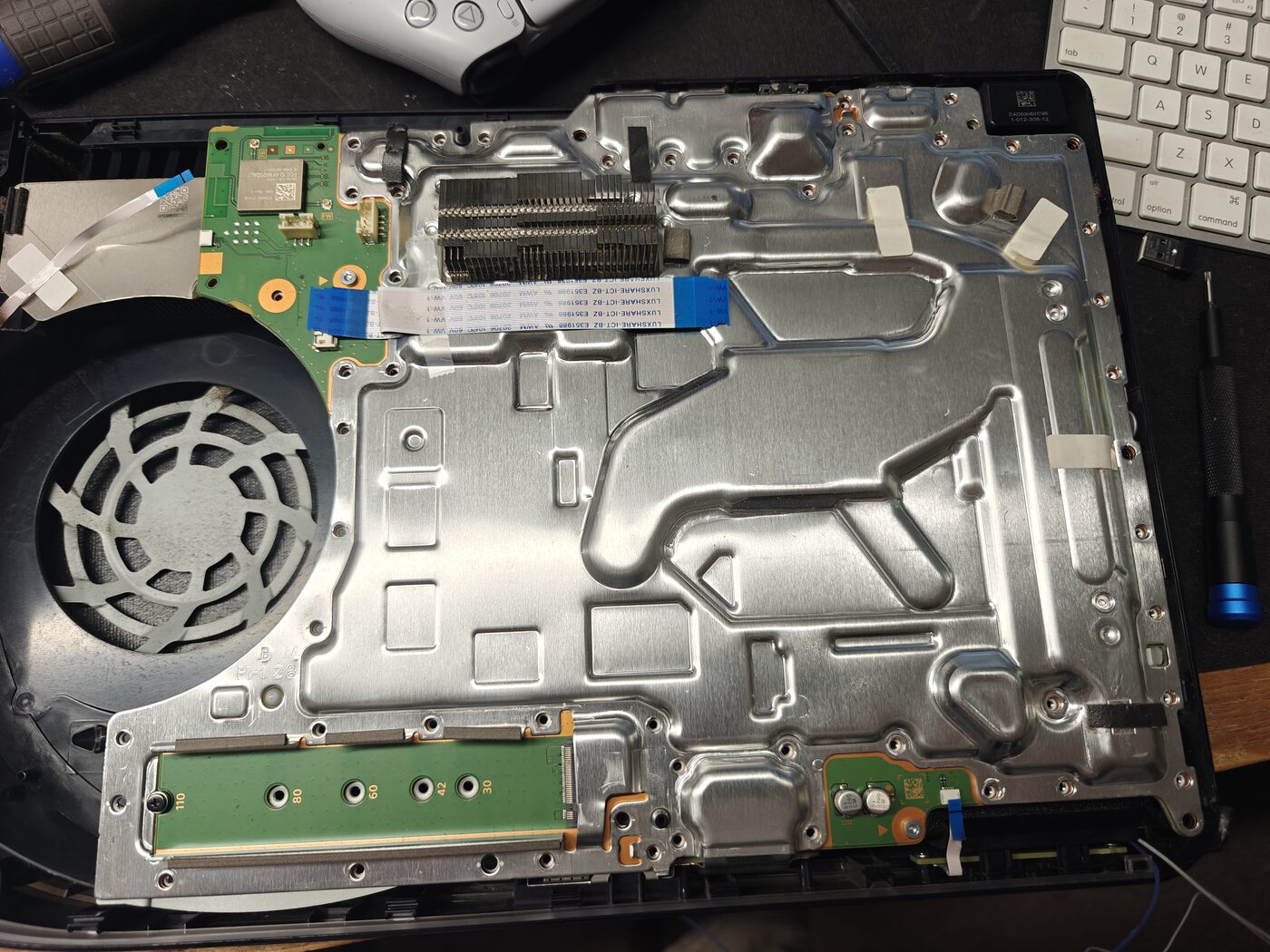 PlayStation 5 disassembled for repair with controller nearby