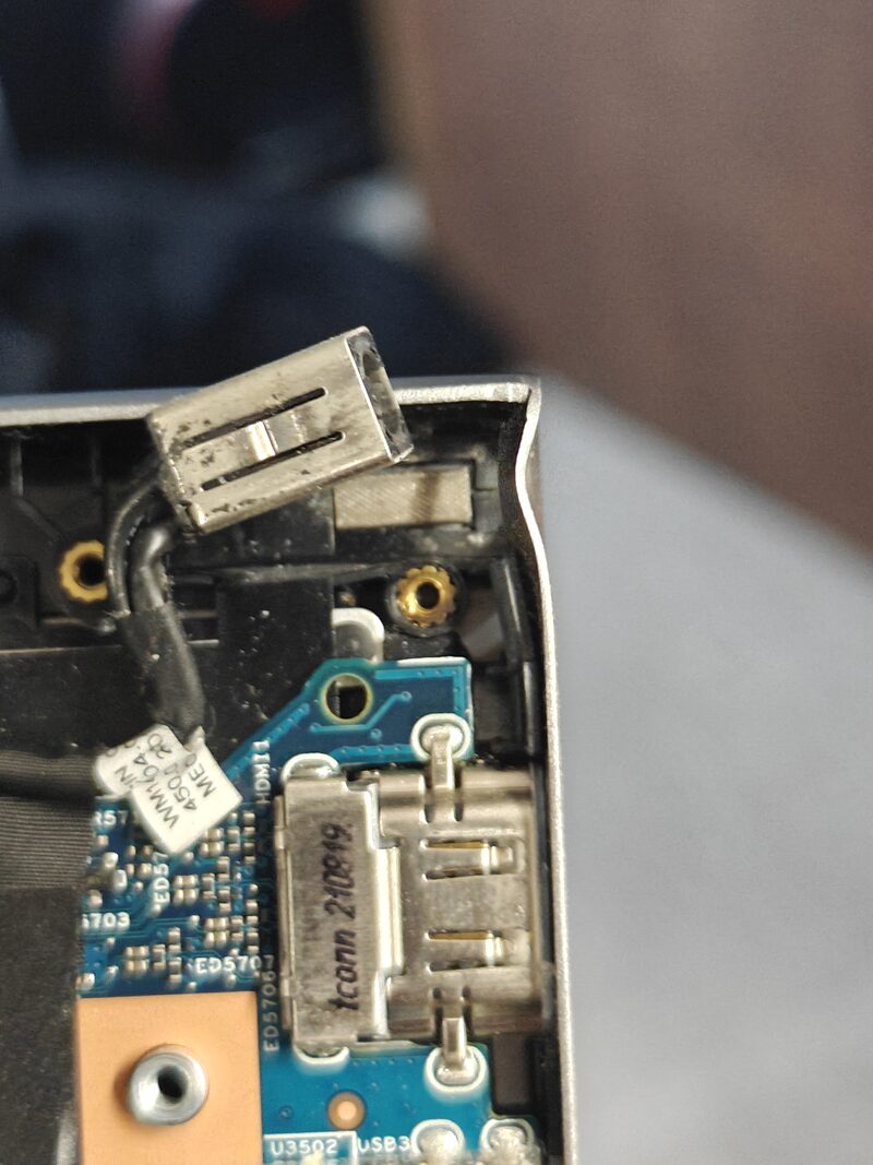 Close-up of a damaged laptop charging port under repair